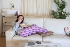 girl lying on sofa eating junk food