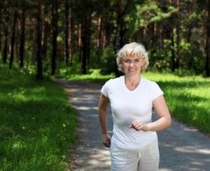 Senior woman walking for exercise in a field