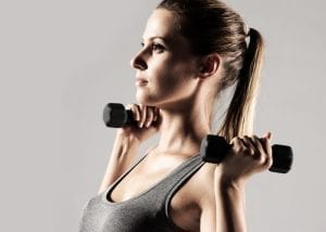 Young woman lifting dumbbells above her shoulders