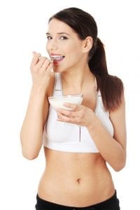 Young dark haired woman eating yoghurt