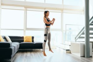 Fit young woman doing Jump Squats in her loungeroom