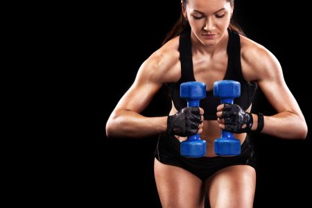 Fit, brunette woman working out with dumbbells