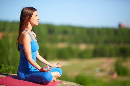 Young, brunette woman doing the Lotus pose outdoors
