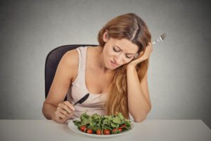 Unhappy woman eating a salad