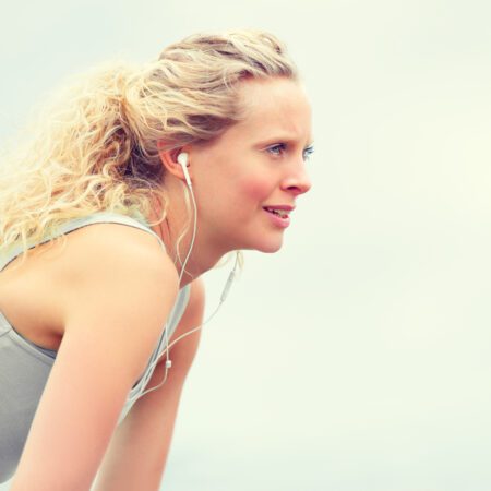 Young, blonde women exercising wearing ear pods.